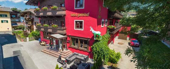 Hausansicht Hotel Gamshof Außenansicht des Hotel Gamshof mit roter Fassade, Holzbalkonen und einer Gams-Skulptur.