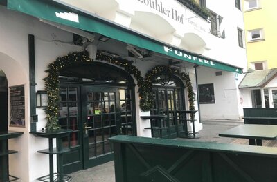Eingangsbereich des Lokals Fünferl mit grüner Markise und weihnachtlicher Girlande über den Rundbogentüren.