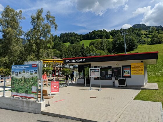 Talstation der DSL Bichlalm mit Ticket-Service, Informationstafeln und bewaldetem Hang im Hintergrund.