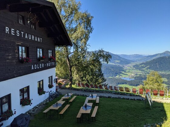 Außenansicht der Adler-Hütte mit Terrasse und Blick auf ein bewaldetes Tal.
