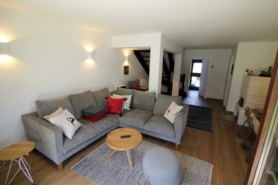Wohnbereich Apartment Kitzkamm Modernes Wohnzimmer mit grauem Ecksofa, Holztisch und Teppich in einer Ferienwohnung.