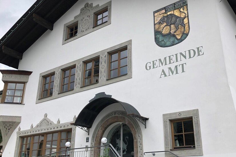 Weiße Fassade des Gemeindeamts Jochberg mit Wappen und Schriftzug.