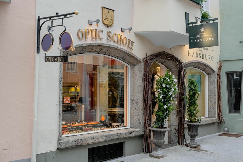 Außenansicht des Optikergeschäfts Optic Schott mit Schaufenster und dekorativem Brillenschild.