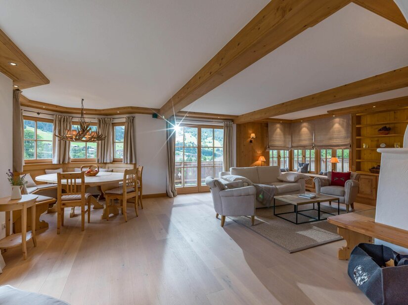 Heller Wohnraum mit Holzbalkendecke, Sitzecke, Sofa und Esstisch aus Holz.