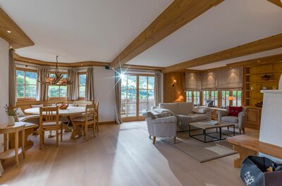 Heller Wohnraum mit Holzbalkendecke, Sitzecke, Sofa und Esstisch aus Holz.