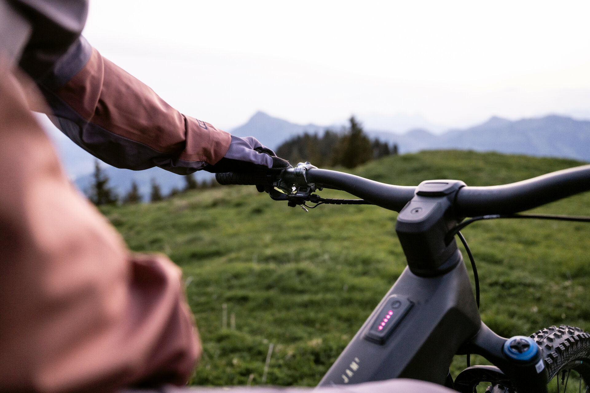 Ein E-Biker auf einem FAZUA-betriebenen E-Bike hält den Lenker und blickt in Kitzbühel auf die umliegende Berglandschaft.