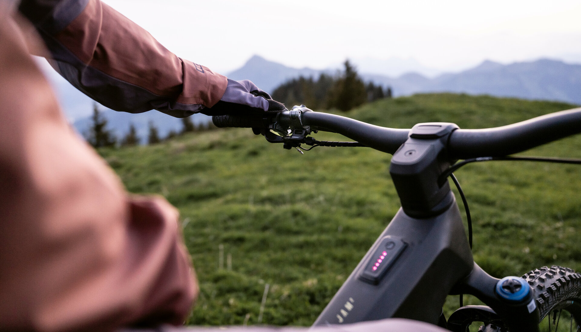 Ein E-Biker auf einem FAZUA-betriebenen E-Bike hält den Lenker und blickt in Kitzbühel auf die umliegende Berglandschaft.