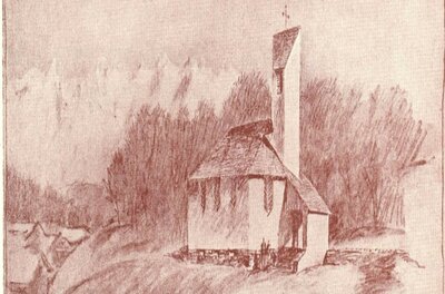 Eine kleine Kirche auf einem Hügel mit einem schmalen, hohen Turm. Umgeben von Bäumen und sanften Hügeln wirkt die Szene ruhig und malerisch.