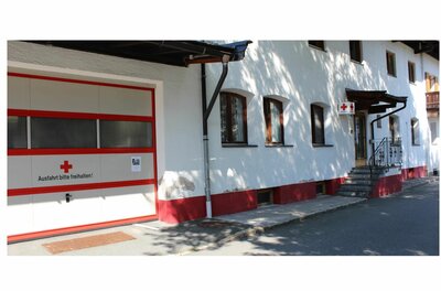 Rettungsstation Rotes Kreuz Weißes Gebäude mit Garagentor des Roten Kreuzes und Treppenaufgang.