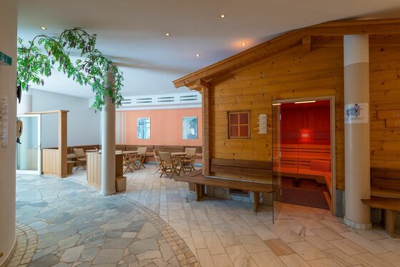 Saunalandschaft innen Ein einladender Wellnessbereich mit einer Holzsauna und gemütlichen Sitzgelegenheiten. Die sanfte Beleuchtung sorgt für eine entspannende Atmosphäre.