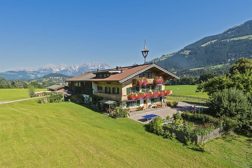Traditionelles Alpenhaus mit Blumenschmuck vor Bergpanorama.