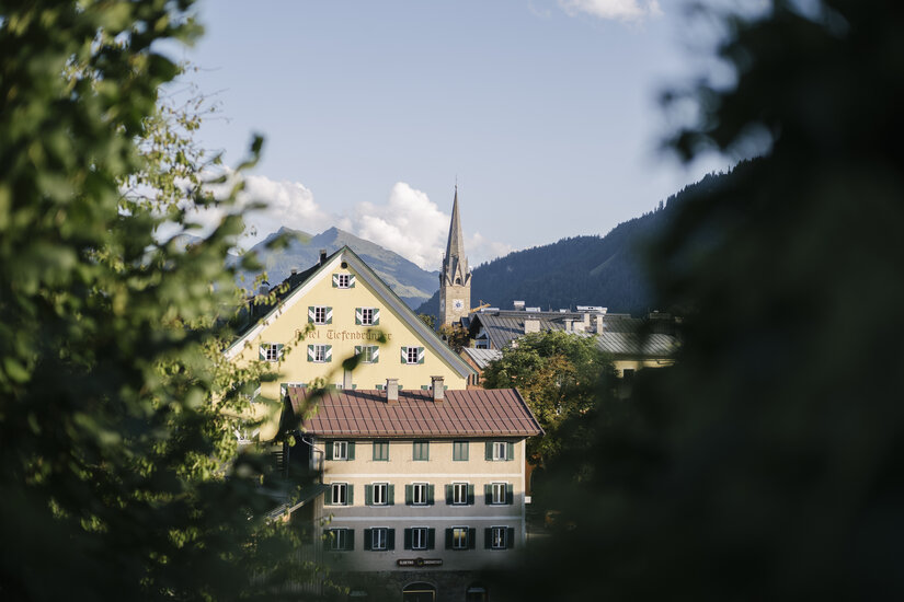 Kitzbühel mit bunten Häusern und Kirche, umgeben von Bergen und klarem Himmel.