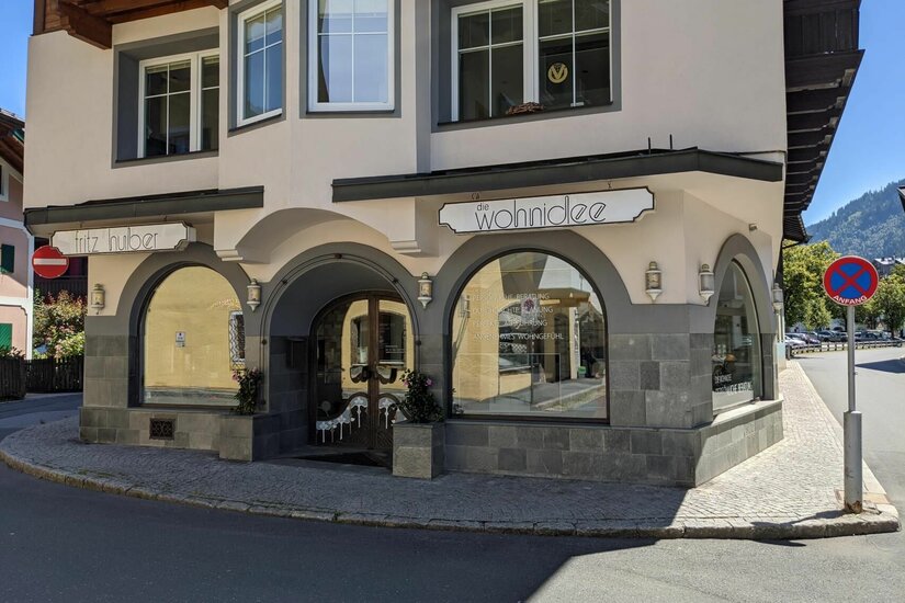 Außenansicht des Geschäfts Die Wohnidee mit Rundbogenfenstern und Steinfassade an einer Straßenecke.