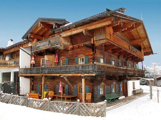 Apartment Neuhaus im Winter Mehrstöckiges Holzhaus im Alpenstil mit Balkonen in einer verschneiten Winterlandschaft.