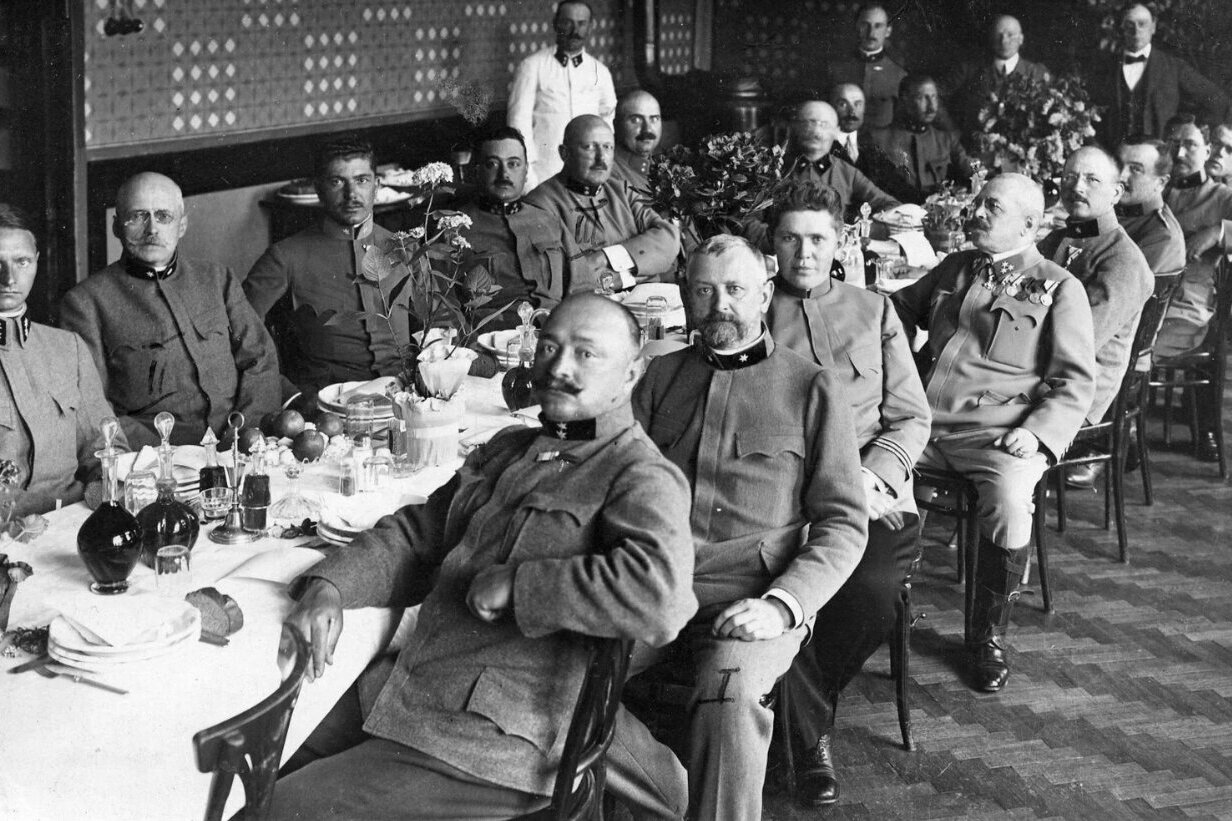 Men in Nazi uniforms are seated at a laid table