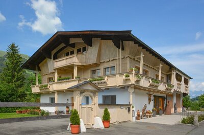 Die alte Bildhauerei Zweistöckiges Gebäude in Holzbauweise mit Balkonen, Blumenkästen und einem kleinen Holztor im Vordergrund.