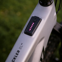 Ein E-Bike mit einem modernen Design, das eine digitale Anzeige mit leuchtenden LEDs auf dem Rahmen zeigt.