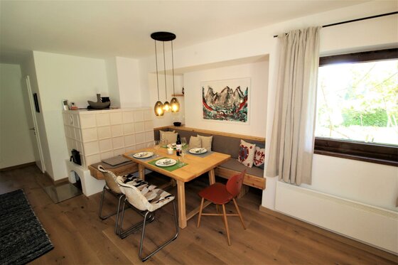 Essbereich Apartment Kitzkamm Moderner Essbereich mit Holztisch, Eckbank, Kachelofen und Fenster.