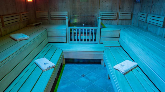 Wellness Center 2 Eine moderne Sauna mit hellblauen Beleuchtungseffekten. Die Holzbank ist sauber und lädt zur Entspannung ein.