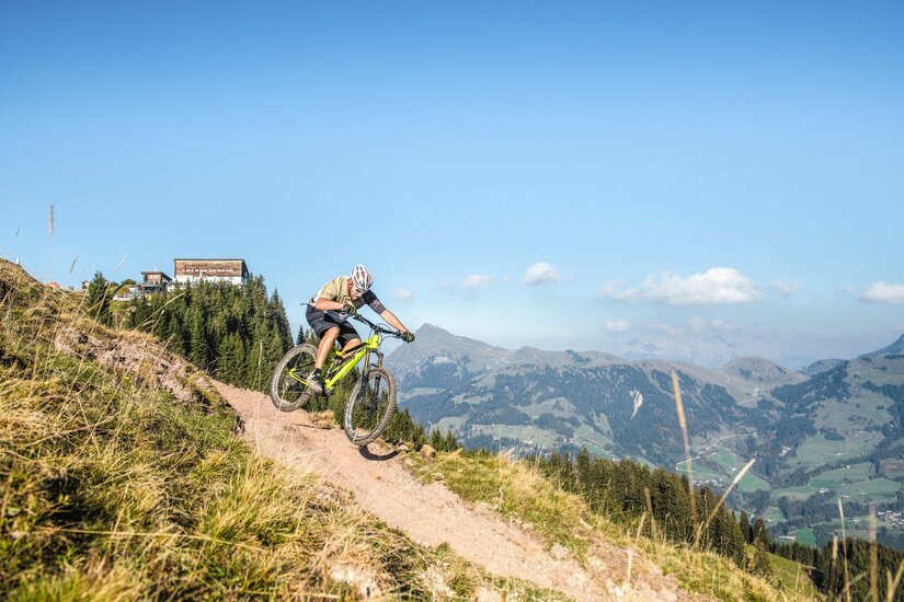 Mountainbiken am Hahnenkamm Ein Mountainbiker fährt auf einem schmalen Pfad am Hahnenkamm bergab.