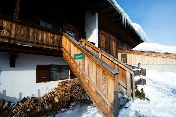 Eingang Hof Hintererb Hölzerner Treppenaufgang zu einem verschneiten Bauernhaus mit Brennholzstapel.