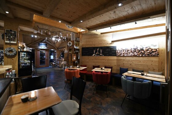 KunsTraum Café Ein gemütliches Restaurant mit Holzwänden und warmem Licht. Die Tische sind mit bunten Stühlen dekoriert und schaffen eine einladende Atmosphäre.