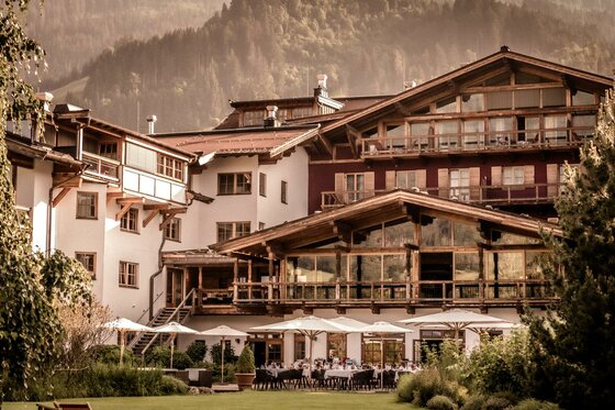 Ein charmantes Hotel in den Bergen mit einer einladenden Terrasse. Wunderschöne Natur umgibt die Gebäude.