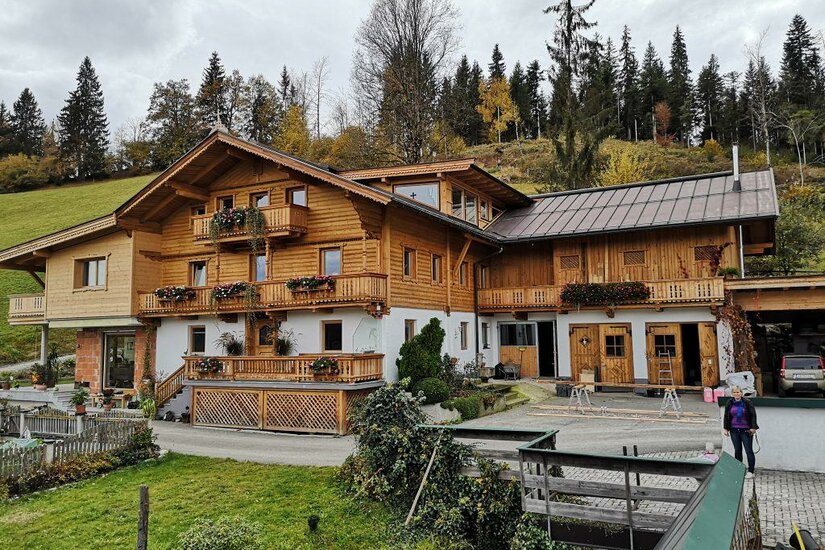 Brandhof Ein traditionelles Holzhaus inmitten von Bäumen und Wiesen. Die Umgebung ist ruhig und einladend.