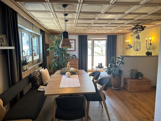 Moderner Essbereich mit Holztisch, gepolsterter Sitzbank und Kassettendecke aus hellem Holz.