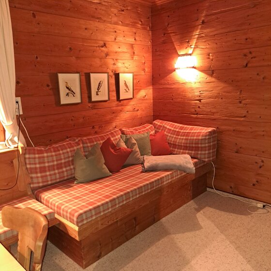 Sitzecke mit karierten Polstern und Kissen in einem holzgetäfelten Raum.