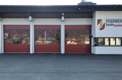 <p>Das Feuerwehrgebäude in Reith mit drei roten Toren und einem klaren Himmel.</p>