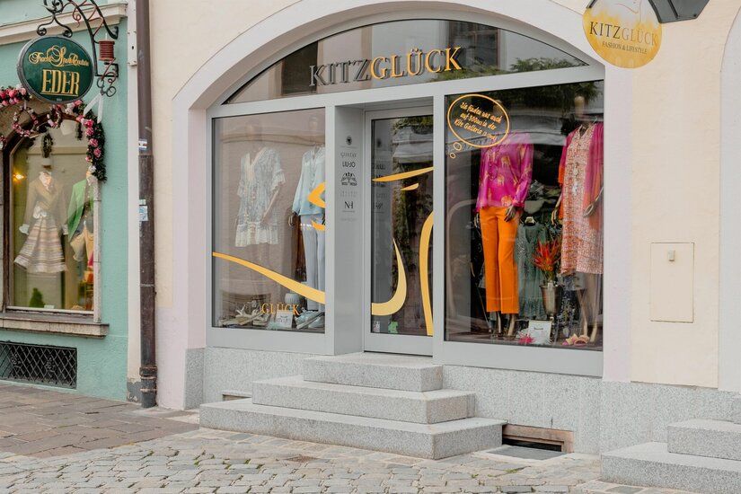 Modegeschäft Kitzglück Eingangsbereich des Modegeschäfts Kitzglück mit Schaufenstern und Steinstufen.