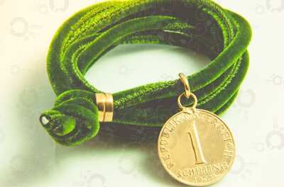 Armband Ein grünes elegantes Samtarmband mit einer goldenen Schillingmünze als Anhänger.