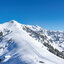 Skitourengebiet Bichlalm in Kitzbühel mit schneebedeckten Hügeln, Nadelbäumen und blauem Himmel.