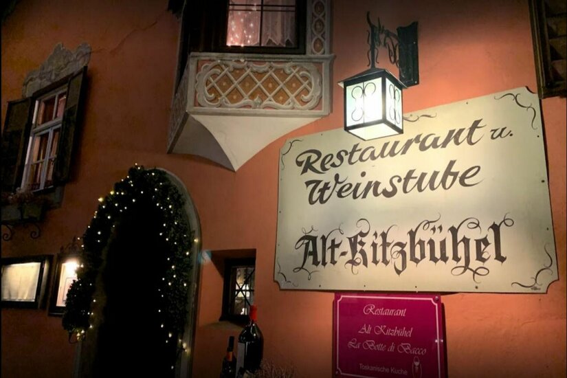 Restaurant Alt-Kitzbühel Außenansicht des Restaurants Alt-Kitzbühel mit beleuchtetem Schild, Laterne und dekoriertem Eingang bei Nacht.