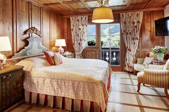 Rustikales Hotelzimmer mit Doppelbett, Holzvertäfelung und Blick auf die Berge.