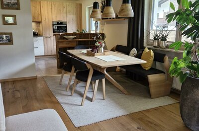 Moderner Essbereich mit Holztisch, Sitzbank und Stühlen unter einer Kassettendecke aus Holz.