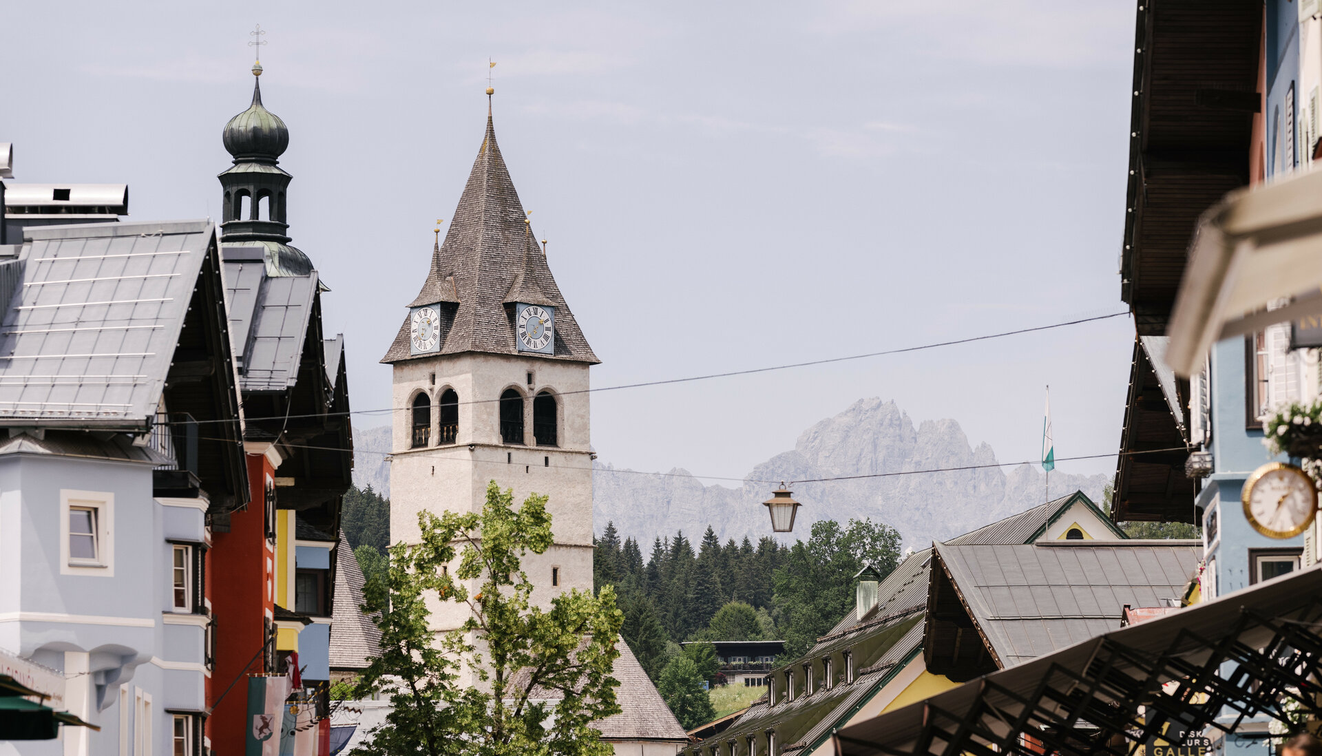 Ein malerischer Blick auf eine Stadt mit einem markanten Kirchturm und bunten Gebäuden im Vordergrund.