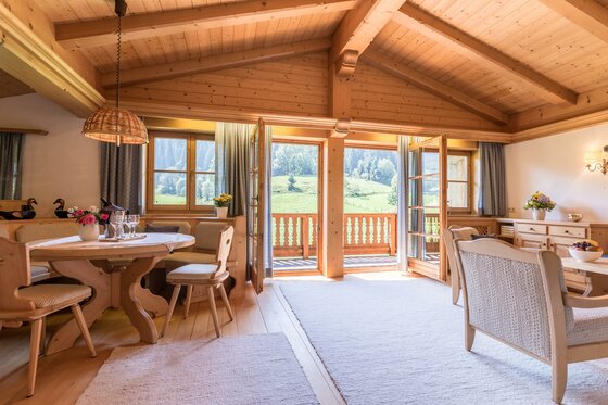 Heller Wohnraum aus Holz mit Esstisch, Sitzecke und Balkonzugang in einer Ferienwohnung.