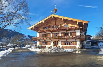Ein traditionelles Chalet im Winter, umgeben von Schnee. Der Himmel ist blau und die Landschaft ist malerisch.