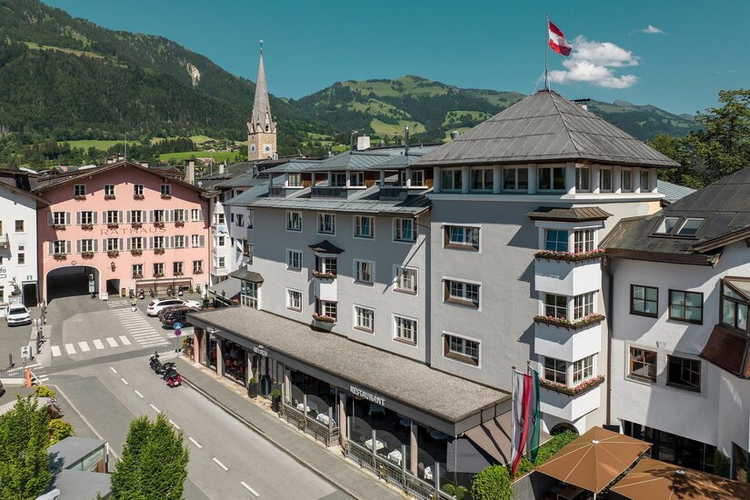 Blick auf das Hotel Das Reisch und das Rathaus in Kitzbühel vor einer Bergkulisse.