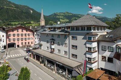 Blick auf das Hotel Das Reisch und das Rathaus in Kitzbühel vor einer Bergkulisse.