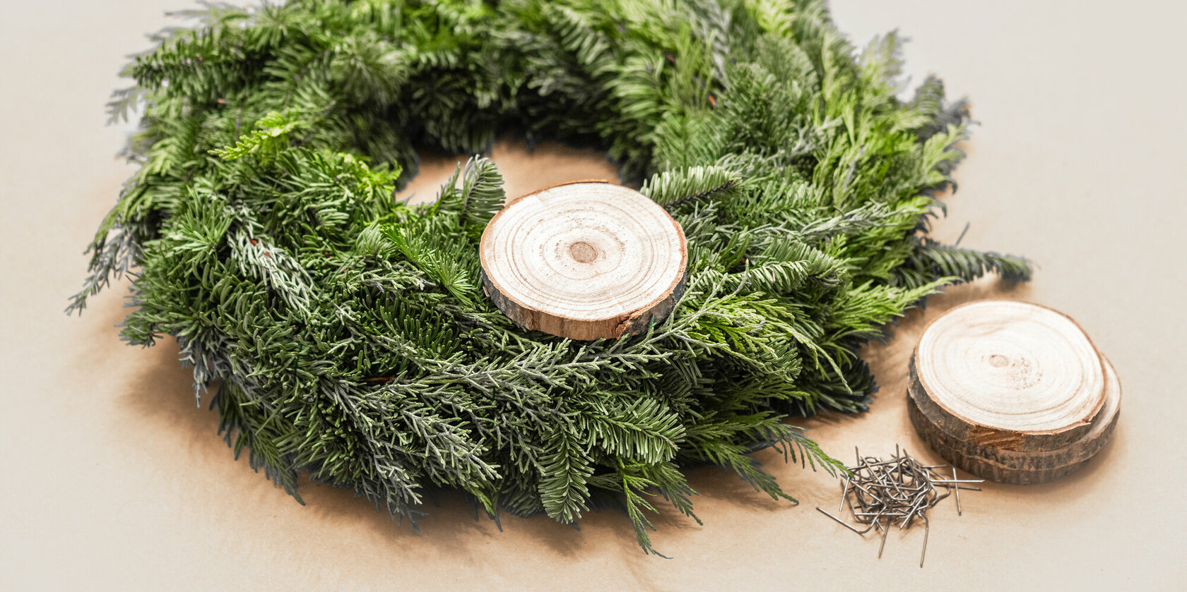 A green Advent wreath onto which small wooden discs are attached