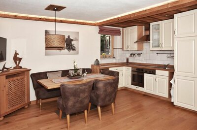 Moderne Küche mit angrenzender Essecke aus Holz und braunen Polstermöbeln.