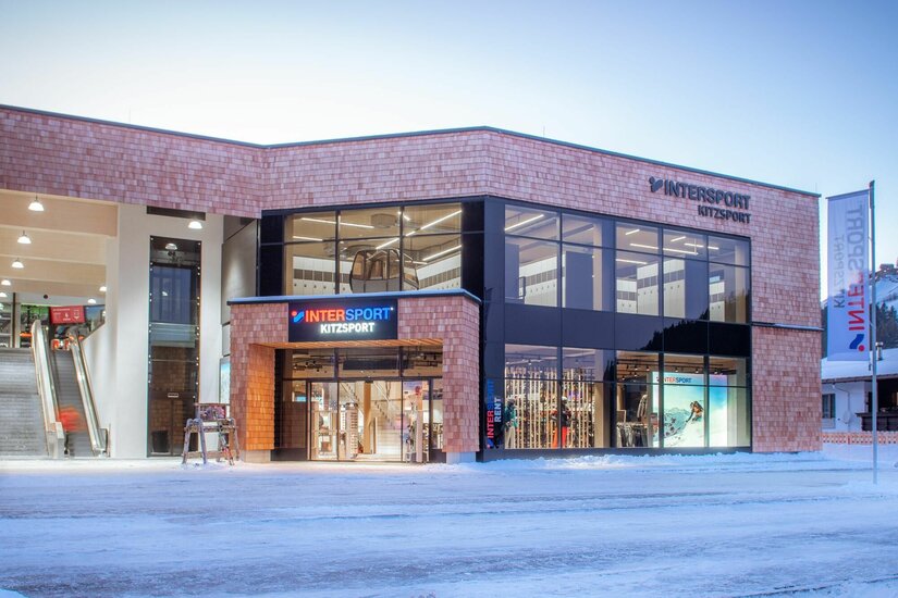Modernes Sportgeschäft mit Holzfassade und großen Glasfronten im Winter.