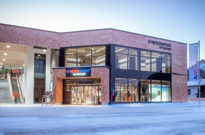 Modernes Sportgeschäft mit Holzfassade und großen Glasfronten im Winter.