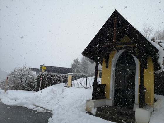 Ölbergkapelle im Winter Kleine gelbe Kapelle mit dunklem Holzdach bei starkem Schneefall im Winter.