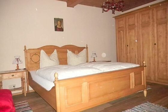 Rustikales Doppelbett aus hellem Holz mit weißer Bettwäsche und passendem Kleiderschrank.