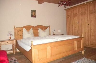 Doppelzimmer im Seiwaldhof Rustikales Doppelbett aus hellem Holz mit weißer Bettwäsche und passendem Kleiderschrank.
