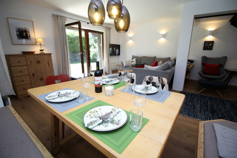 Essbereich im Apartment Kitzkamm Gedeckter Holztisch in einem modernen Wohn- und Essbereich mit Sofa und Terrassenzugang.